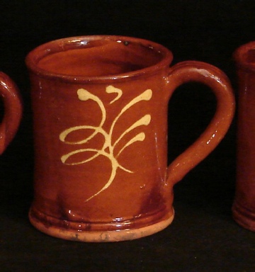 redware mug with feather motif